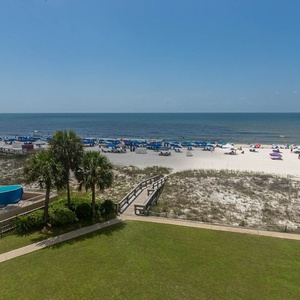 This view showcases a vibrant beachfront with colorful umbrellas, a pool area, and lush greenery, perfect for relaxation