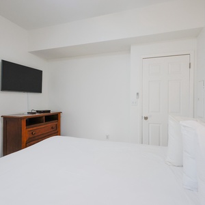 Cozy guest bedroom featuring a comfortable queen bed, a wooden dresser, and a flat-screen TV for relaxing evenings