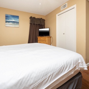 Master sutie bedroom featuring a king bed, a flat-screen TV, and warm tones, perfect for relaxation after a day at the beach