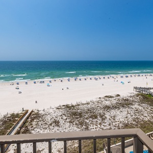 Expansive beachfront view showcasing soft white sand and gentle waves under a bright blue sky, perfect for relaxation