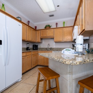 Prepare meals in the spacious kitchen featuring ample counter space, wooden cabinetry, and white appliances