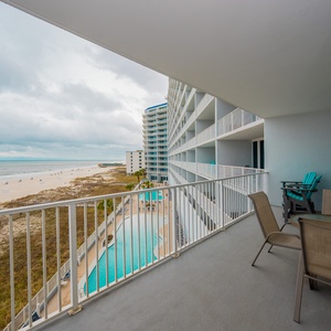 Enjoy a beachfront view from the balcony, featuring comfortable seating and a refreshing pool below