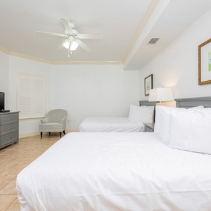 Experience restful nights in this cozy guest bedroom with two double beds, cozy chair, dresser, and TV