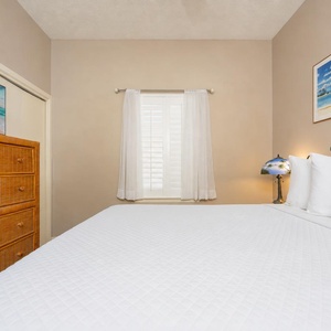 Rest in this comfortable guest bedroom featuring a queen bed, dresser, and natural light from the window