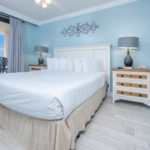Unwind in the serene master bedroom featuring a comfortable king bed, charming decor, and beachfront balcony access