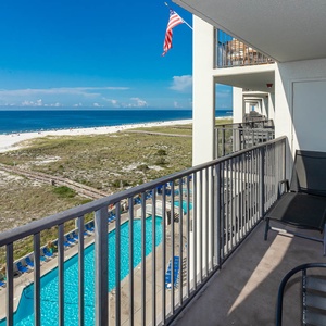 Balcony view showcasing the inviting pool area and the expansive beach with vibrant blue waters and white sand