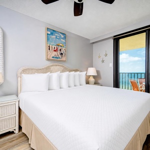 Master bedroom featuring a king bed, coastal artwork, and sliding glass doors leading to the beachfront balcony