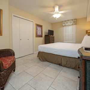 Brightly decorated guest room featuring a king bed, wicker seating, and a TV, creating a relaxing atmosphere for guests