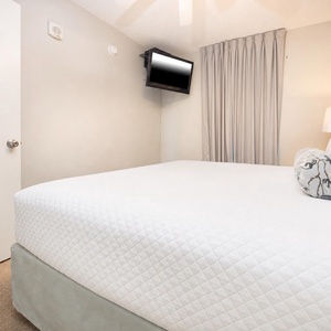 Rest in this comfortable bedroom featuring a king bed, a mounted TV, and soft lighting for a relaxing stay