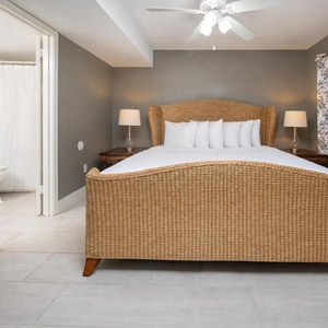 Master bedroom featuring a woven bed frame, king bed, soft linens, and elegant floral curtains for a serene retreat