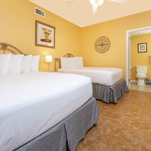 Rest in this cheerful guest room featuring two comfortable queen beds, warm tones, and en-suite bathroom