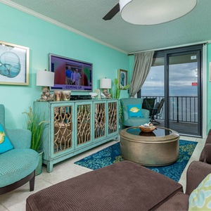 Bright turquoise walls and cozy seating and queen sleeper create a welcoming living room with a view of the balcony