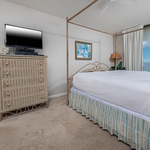 Enjoy restful nights in the master bedroom featuring a four-poster king bed, dresser, and a TV