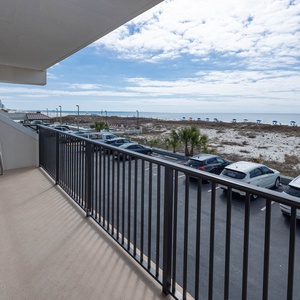 Enjoy a relaxing view from the balcony with seating, overlooking the beach and nearby umbrellas