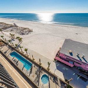 Enjoy the serene view of the coastline and inviting pool area from your spacious balcony, overlooking the Pink Pony Pub