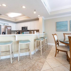 Gather around the breakfast bar with stylish stools, or enjoy meals at the round dining table beside serene artwork