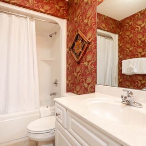 Enjoy a relaxing shower after a day at the beach in this guest bath with stylish accents and fluffy towels