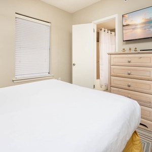 Experience restful nights in this inviting guest bedroom featuring a plush queen bed, a TV, and colorful decor