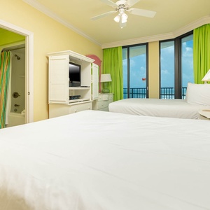 Inviting guest bedroom with two queen beds, bright decor, and large windows showcasing the beautiful view