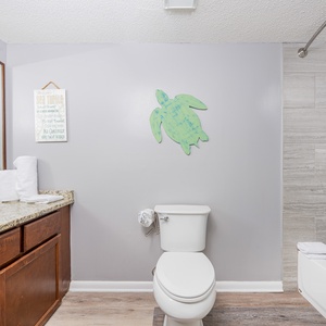 Stylish guest bathroom featuring a granite vanity, decorative accents, and a relaxing tub with a shower