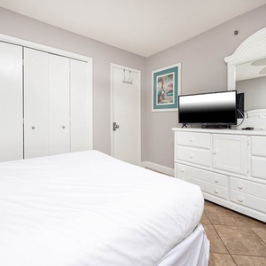 Inviting guest bedroom featuring a queen and twin bed, a TV, and stylish decor with a view into the adjoining bathroom