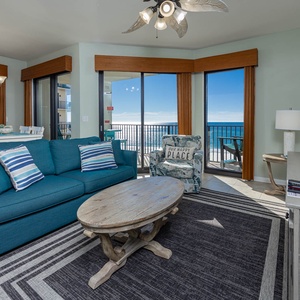 Living area features a teal sofa with queen sleeper, a wooden coffee table, and stunning gulf views