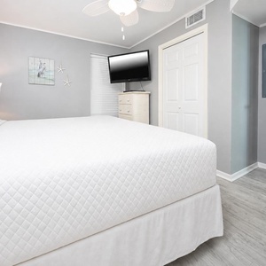 Cozy bedroom featuring a plush king bed, a mounted TV, and coastal decor for a relaxing retreat