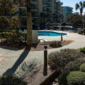 Stroll along the winding path surrounded by greenery, leading to warm pools perfect for relaxation under the sun