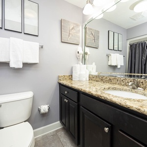Stylish guest bath featuring a granite countertop, ample towels, and decorative art for a refreshing retreat