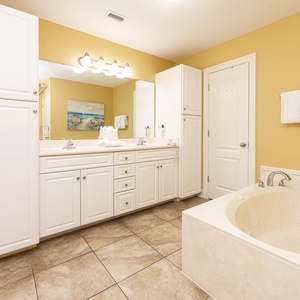Soothing master bathroom featuring a jetted tub, spacious vanity, and warm yellow walls for a relaxing retreat
