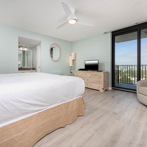 Relax in the spacious master suite featuring a cozy king bed, a TV, and balcony access