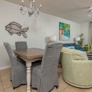 Seating in vibrant greens and blues complements the dining area, offering a welcoming space with views of the beach
