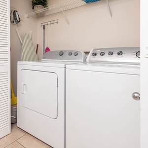 Laundry area featuring a washer and dryer, with shelving for storage and an ironing board for added convenience