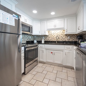 This modern kitchen features stainless appliances, granite countertops, and a stylish tile backsplash for delightful cooking