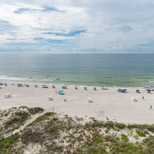 This inviting space offers a breathtaking beachfront view with colorful umbrellas dotting the sandy shore