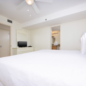 This bedroom features a plush king bed, a flat-screen TV, and an adjoining bathroom with elegant granite countertops