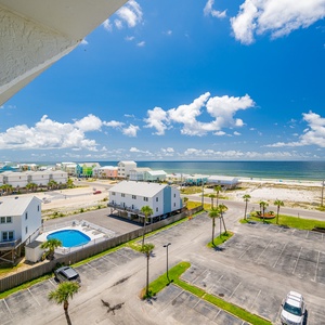 Enjoy a stunning beach view from this bright space, showcasing vibrant coastal homes and a refreshing pool below