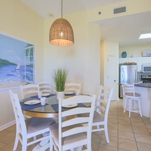 Dining area featuring a round table with white chairs, complemented by a vibrant mural and a modern breakfast bar
