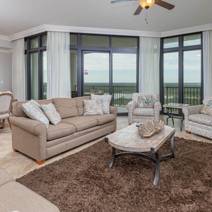 The living area features plush seating, a stylish chandelier, and expansive windows offering a serene view