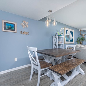 This inviting living area features a rustic dining table, coastal decor, and a beautiful view from the balcony