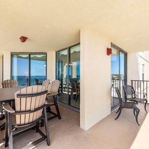 The spacious balcony features a dining table and chairs, offering a relaxing spot to enjoy the beautiful beach view