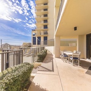 Spacious beach patio features a dining set and lush greenery, perfect for enjoying the sun and relaxing by the pool