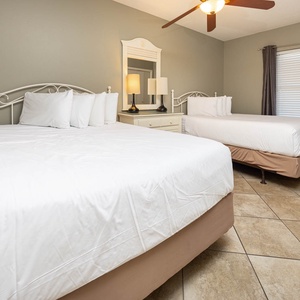 Rest in the inviting guest bedroom featuring two queen beds, soft lighting, and a stylish dresser for your convenience