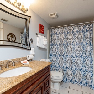 Master bathroom featuring a stylish granite countertop, elegant mirror, and a colorful shower curtain for a refreshing vibe