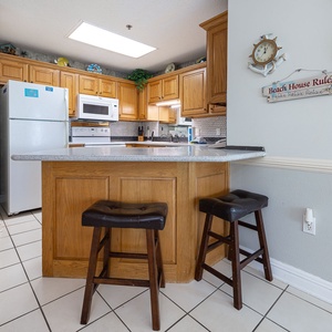 Warm wood cabinetry complements the granite countertop and breakfast bar, creating a welcoming space for meal preparation