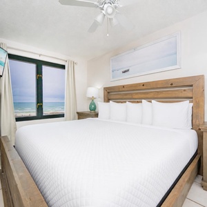 This bedroom features a cozy bed with fluffy pillows and a stunning beachfront view through large windows