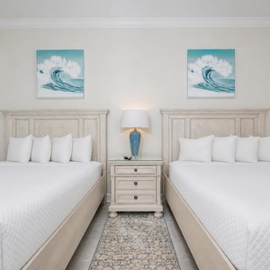 Unwind in this inviting bedroom featuring two queen beds and coastal artwork for a restful getaway
