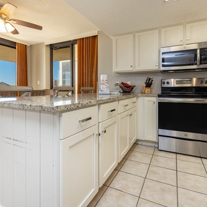 Bright kitchen area featuring granite countertops, modern appliances, and a dining space with woven chairs and a view