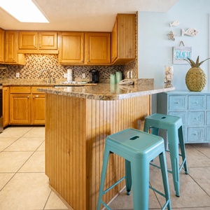 Wood cabinetry and granite countertops define this kitchen area, featuring a stylish backsplash and Keurig coffee maker