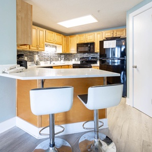 Sit at the sleek bar stools and enjoy a meal in the inviting kitchen with ample counter space and black appliances